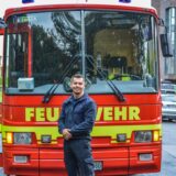 Feuerwehrmann Romano Bredehorn, der bei Temptation Island 2025 als Verführer teilnimmt, steht vor einem Wagen der Feuerwehr Dortmund.