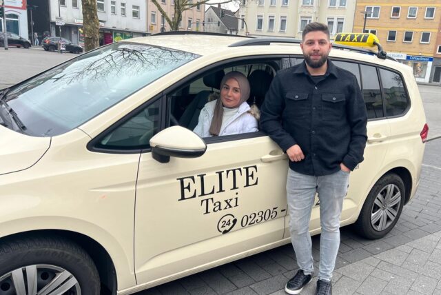 Esra Oruc und ein Mitarbeiter stehen an ihrem Taxi des Taxiunternehmens Elite aus Castrop-Rauxel.