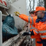 Zwei Mitarbeiter des EUV packen einen blauen Müllsack ins Müllauto.