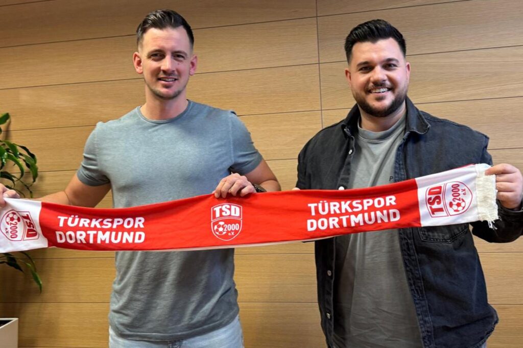 Seyhan Adigüzel und Maximilian Borchmann halten gemeinsam einen Türkspor-Schal hoch. Seyhan Adigüzel und Maximilian Borchmann halten gemeinsam einen Türkspor-Schal hoch.