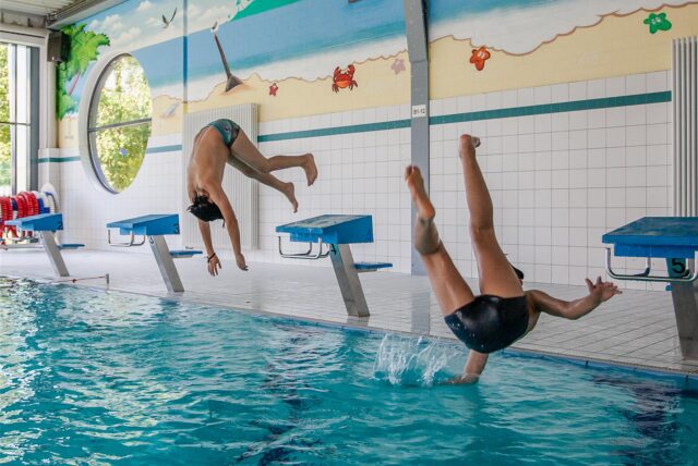 Zwei Jugendliche springen in ein Becken.