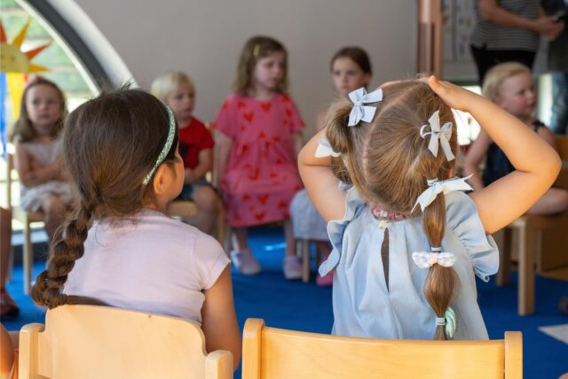 Kinder sitzen in einem Stuhlkreis.