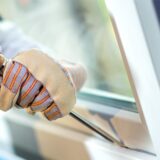 Behandschuhte Hände hebeln ein Fenster mit einem Schraubendreher auf.