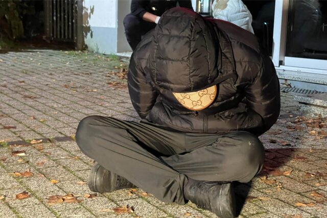 Ein junger Mann sitzt auf dem Boden. Er wurde festgenommen.