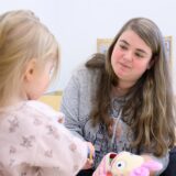 Eine Erzieherin mit einem Kind in einer Kindergartengruppe.