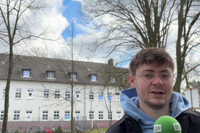Vincent Rastfeld steht vor der Harkortschule in Marl. Auf dem Dach der Schule befindet sich eine der 22 Warnsirenen aus Marl.