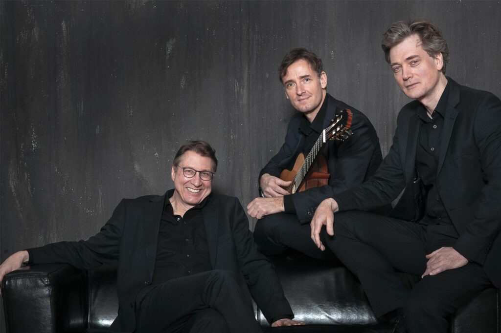Alexander Leidolph, Thomas Etschmann und Mikhail Antropov sitzen auf einem schwarzen Sofa. Alexander Leidolph, Thomas Etschmann und Mikhail Antropov sitzen auf einem schwarzen Sofa.