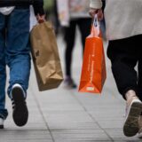Menschen mit Einkaufstaschen gehen an einem verkaufsoffenen Sonntag in einer Fußgängerzone in NRW shoppen.
