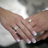 Eine Frauenhand und eine Männerhand tragen Eheringe
