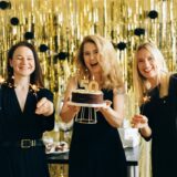 Drei Frauen feiern einen 50. Geburtstag – mit Wunderkerzen und einem Kuchen.