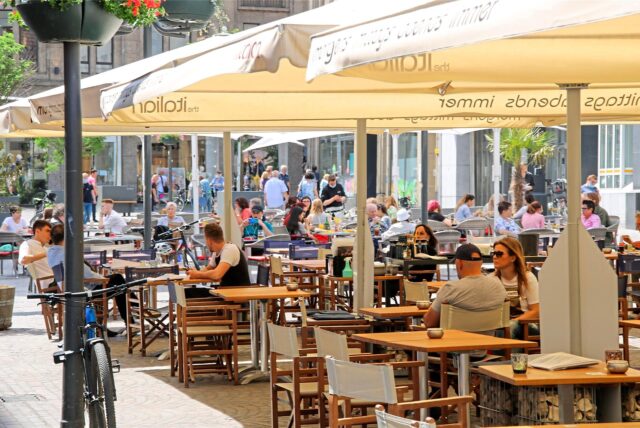 Menschen sitzen an Tischen auf dem Altstadtmarkt in Recklinghausen.