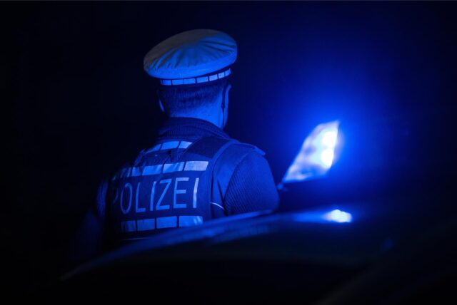 Ein Polizist wird von einem Blaulicht angeleuchtet