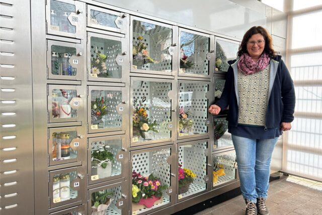 Eine Frau steht vor einem Verkaufsautomaten in Datteln, deren Kästen mit Sträußen gefüllt sind.