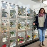 Eine Frau steht vor einem Verkaufsautomaten in Datteln, deren Kästen mit Sträußen gefüllt sind.