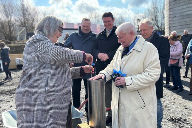 Stiftungsvorsitzende Elisabeth Grümer (r.) und die stellvertretende Fördervereinsvorsitzende des Kinderhospizes, Anja Butschkau, schrauben den Grundstein-Zylinder mit Dokumenten der Zeit zu, im Hintergrund Landrat Bodo Klimpel und Bürgermeister Rajko Kranwanja.