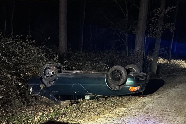 Ein grünes Auto liegt auf dem Dach auf einem Feldweg
