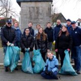 Mitglieder des Lions Clubs sowie des Leo Clubs Herten stehen vor dem Ehrenmal in Herten-Westerholt und halten gut gefüllte blaue Müllsäcke in den Händen.