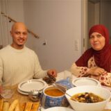 Ein junger Mann und eine Frau mit Kopftuch sitzen an einem gedeckten Tisch.