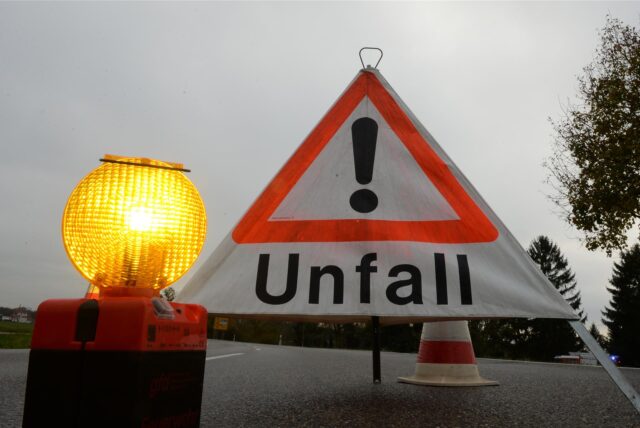 Ein Warnschild mit der Aufschrift „Unfall“ und eine Signalleuchte stehen auf einer Fahrbahn.