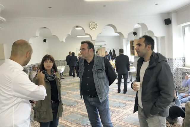 Drei Interessierte lassen sich von einem Gemeindemitglied der Al-Rahma Moschee etwas erklären.