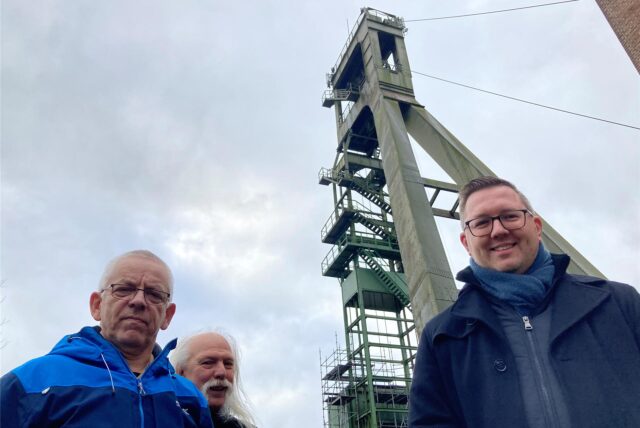 Die Erzschachtfreunde Alfred Dodot, Michael Heyder und Heimatverein-Geschäftsführer Johannes Jansen stehen vor dem Förderturm von Schacht 4, dem früheren Erzschacht.