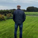 Der Polizist Stefan K. steht mit dem Rücken zur Kamera in einem Garten und blickt in die Natur.