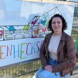 Janna Baierle sitzt in der Hocke vor einem Schild mit der Aufschrift Böckenheckschule.
