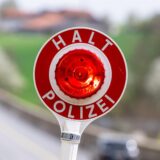 Eine Kelle mit der Aufschrift „Halt Polizei“ wird während einer Verkehrskontrolle hochgehalten.
