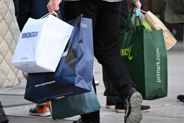 Ein Mann mit Einkaufstüten geht am verkaufsoffenen Sonntag durch eine Innenstadt in NRW.