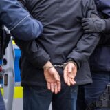 Zwei Beamten führen einen Tatverdächtigen mit Handschellen ab.