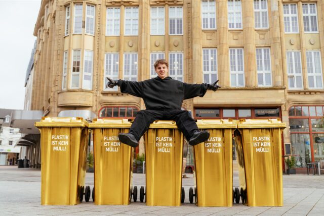 Levi Penell posiert mit goldenen Mülltonnen am Markt in Castrop.