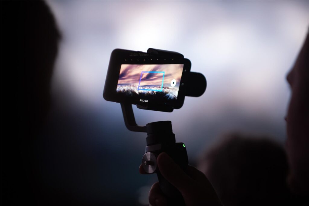 Eine Person hält einen Selfie-Stick in der Hand, an dem ein Smartphone befestigt ist.