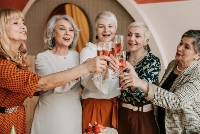 Fünf Frauen stoßen mit Sektgläsern auf den 70. Geburtstag an.