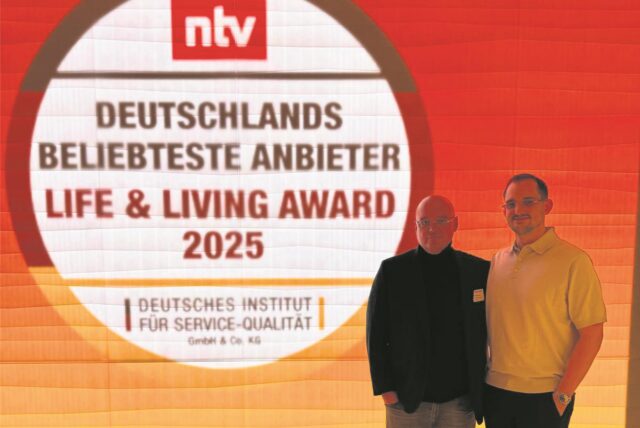Zwei Männer vor dem Logo des Life & Living Award 2025