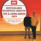 Zwei Männer vor dem Logo des Life & Living Award 2025