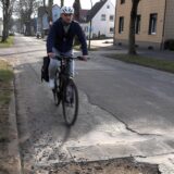 Der Reporter fährt auf seinem Fahrrad über ein Schlagloch.