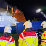 Hertener Feuerwehrmänner stehen vor dem brennenden Dachstuhl an der Feldstraße in Herten-Langenbochum.