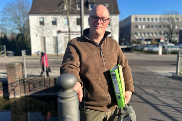 Jonas Engelmeier steht mit einem Aktenordner unter dem Arm auf der Brücke der Wall- und Grabenanlage in Dorsten.