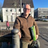 Jonas Engelmeier steht mit einem Aktenordner unter dem Arm auf der Brücke der Wall- und Grabenanlage in Dorsten.