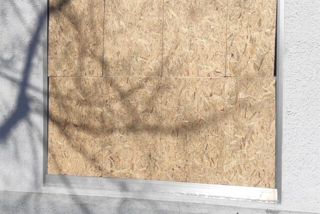 Das Foto zeigt eine Holzplatte, die in eine Schaufensteröffnung eingesetzt ist.