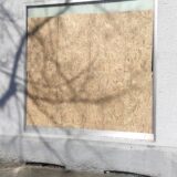Das Foto zeigt eine Holzplatte, die in eine Schaufensteröffnung eingesetzt ist.