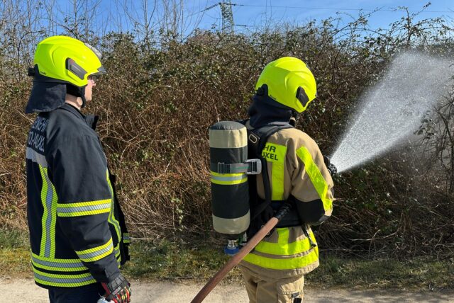 Zwei Feuerwehrleute löschen mit einem C-Schlau einen Flächenbrand.