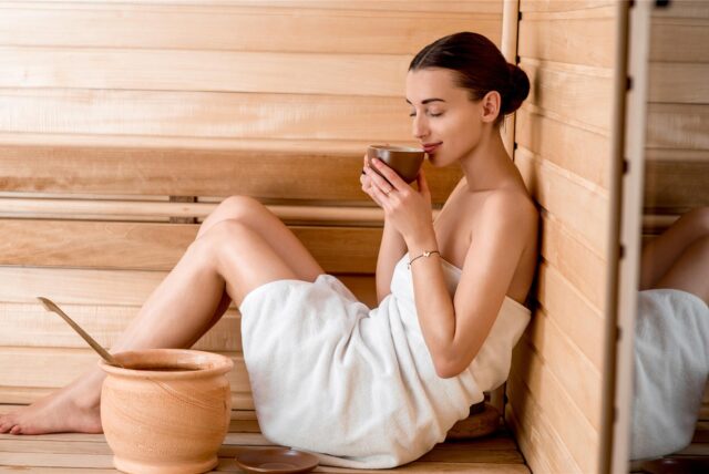 Eine Frau sitzt in einer Sauna.