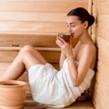 Eine Frau sitzt in einer Sauna.