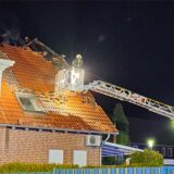 Ein Feuerwehrmann der Hertener Feuerwehr steht im Korb einer ausgefahrenen Drehleiter und blickt auf ein zerstörtes Hausdach.