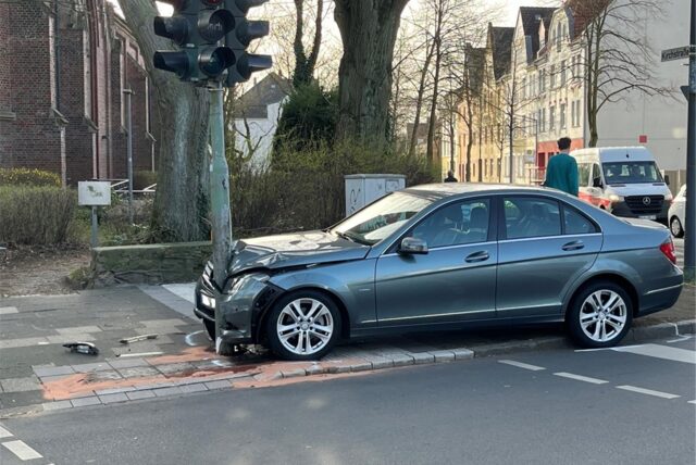 Ein Mercedes mit eingebeulter Front an einer Laterne.