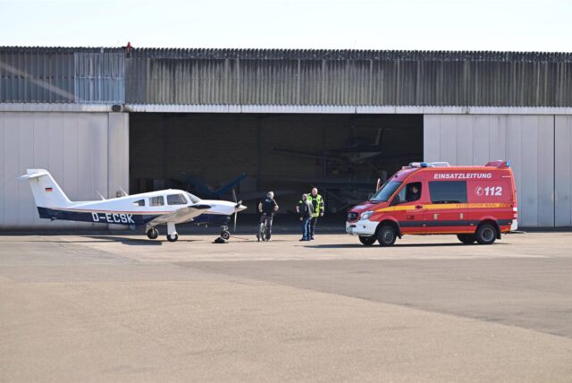 Ein Kleinflugzeug und ein Feuerwehrfahrzeug vor einem Hangar