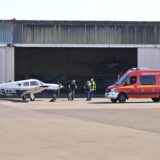 Ein Kleinflugzeug und ein Feuerwehrfahrzeug vor einem Hangar