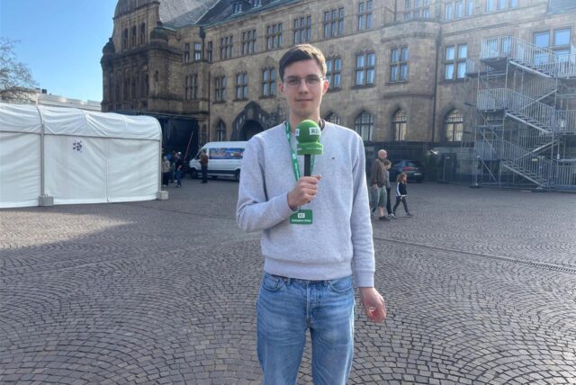 Menschen stehen vor dem Rathaus von Recklinghausen und halten Flyer in der Hand.