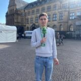 Menschen stehen vor dem Rathaus von Recklinghausen und halten Flyer in der Hand.